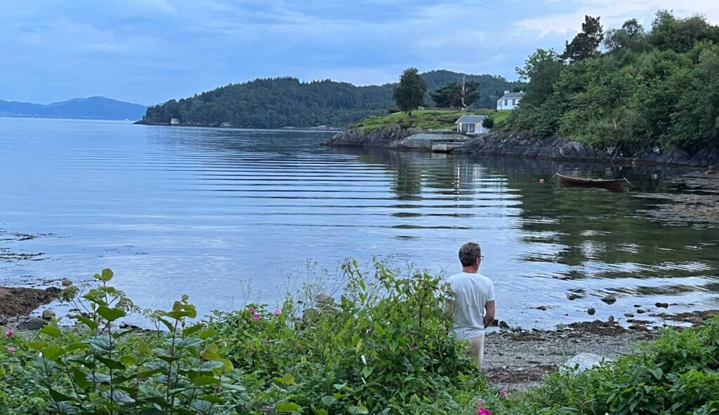 Bilde av mann som står i vannkanten i tellevika, rett ved tomten til boligprosjektet telleviko